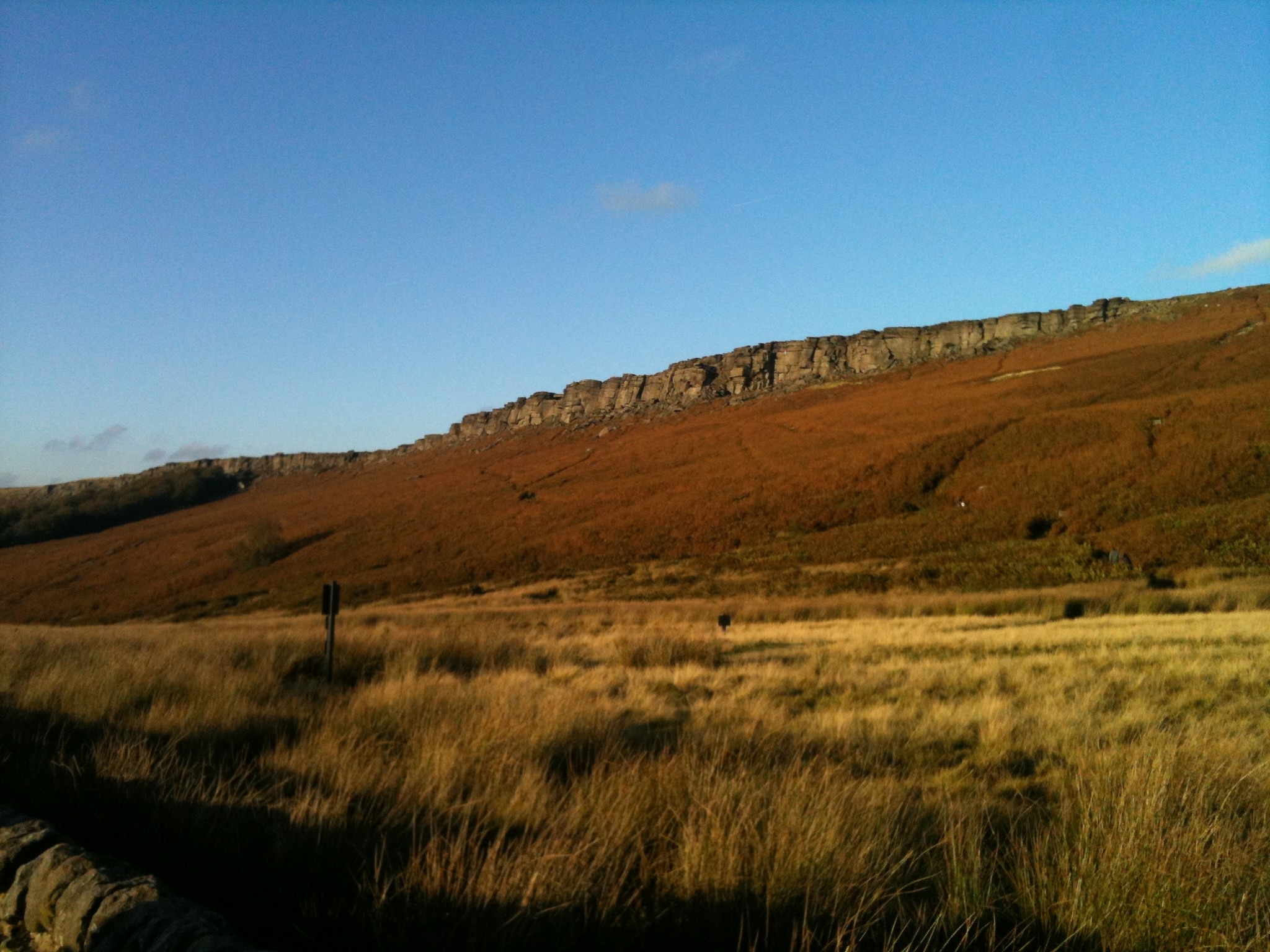 Stanage Edge A rocky outcrop overlooks a heather bathed in golden brown light